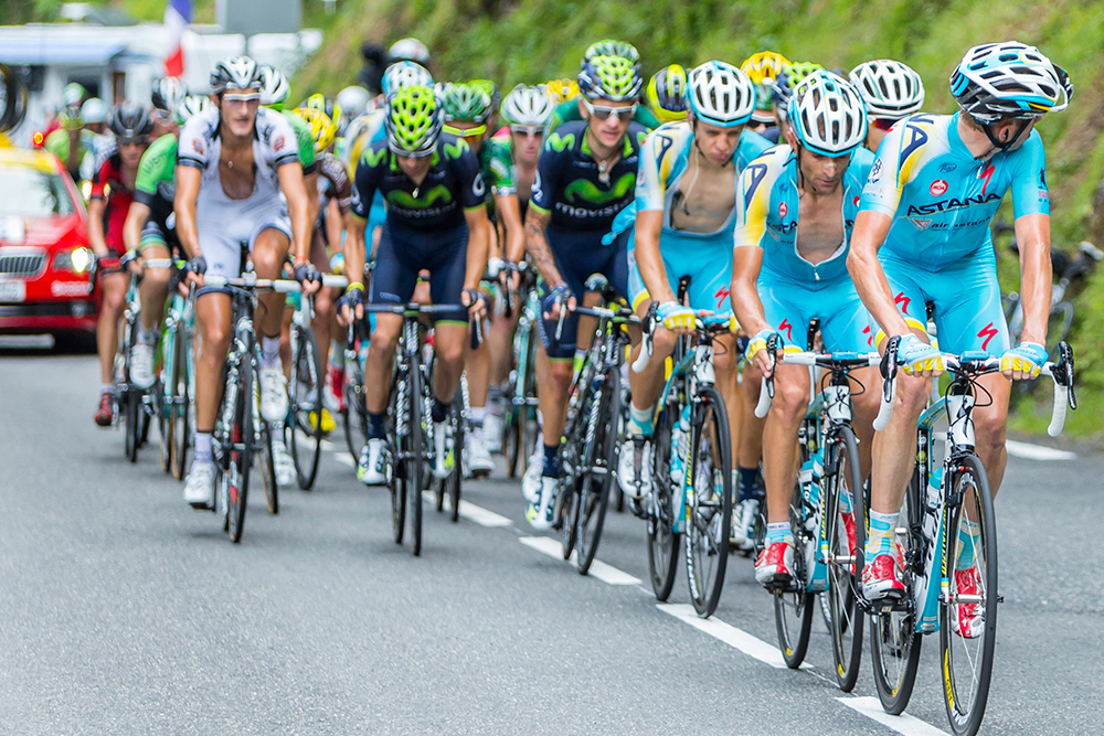 A professional cycling peloton in motion on a road, symbolizing teamwork, timing, and optimized coordination.